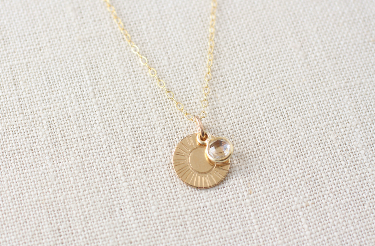 Necklace with a round pendant featuring a clear quartz stone on a linen background