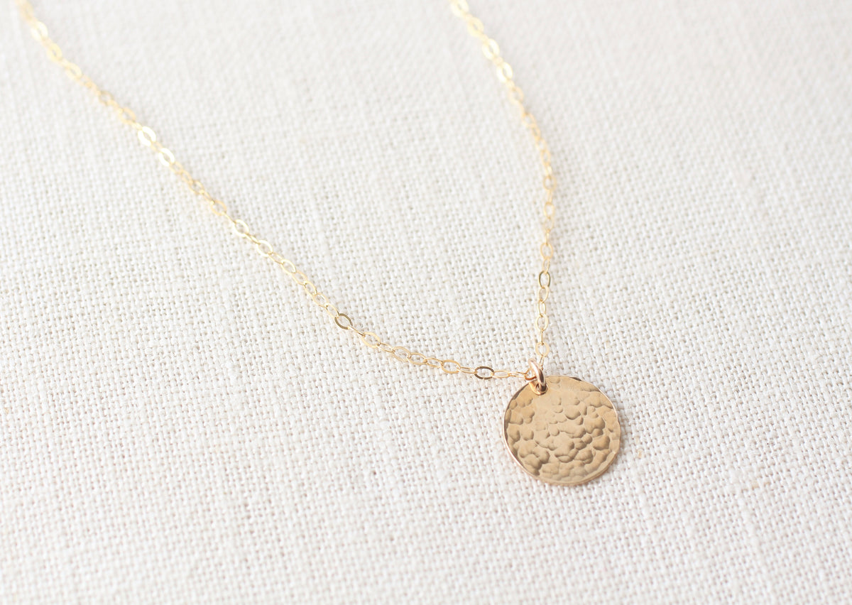 Hammered gold disc necklace linen background 